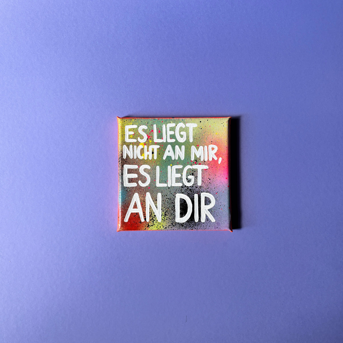 Bunt gesprühtes Kunstwerk mit weißem Schriftzug „Es liegt nicht an mir, es liegt an dir.“