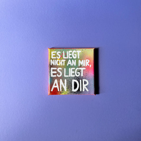 Bunt gesprühtes Kunstwerk mit weißem Schriftzug „Es liegt nicht an mir, es liegt an dir.“