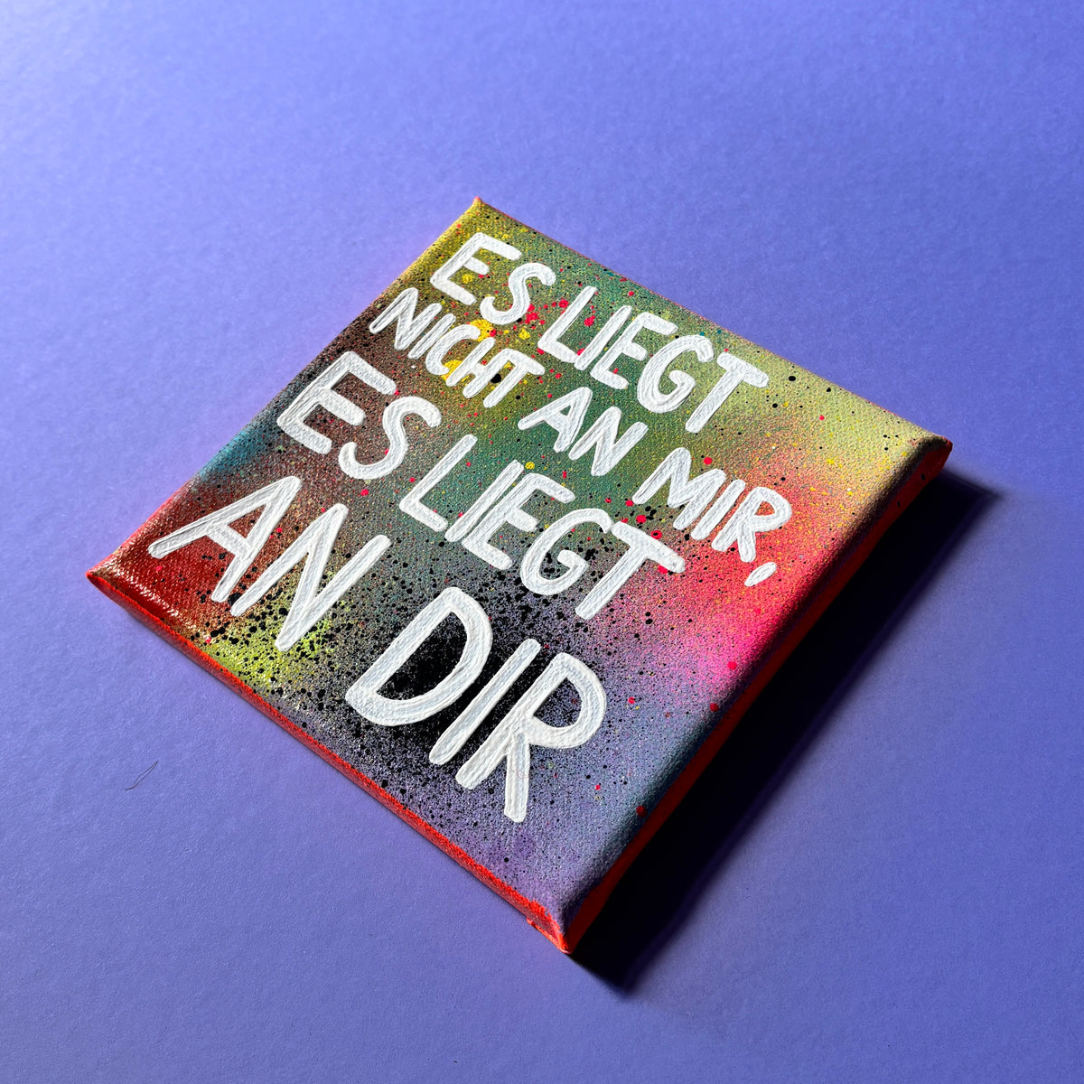 Bunt gesprühtes Kunstwerk mit weißem Schriftzug „Es liegt nicht an mir, es liegt an dir.“ seitlich