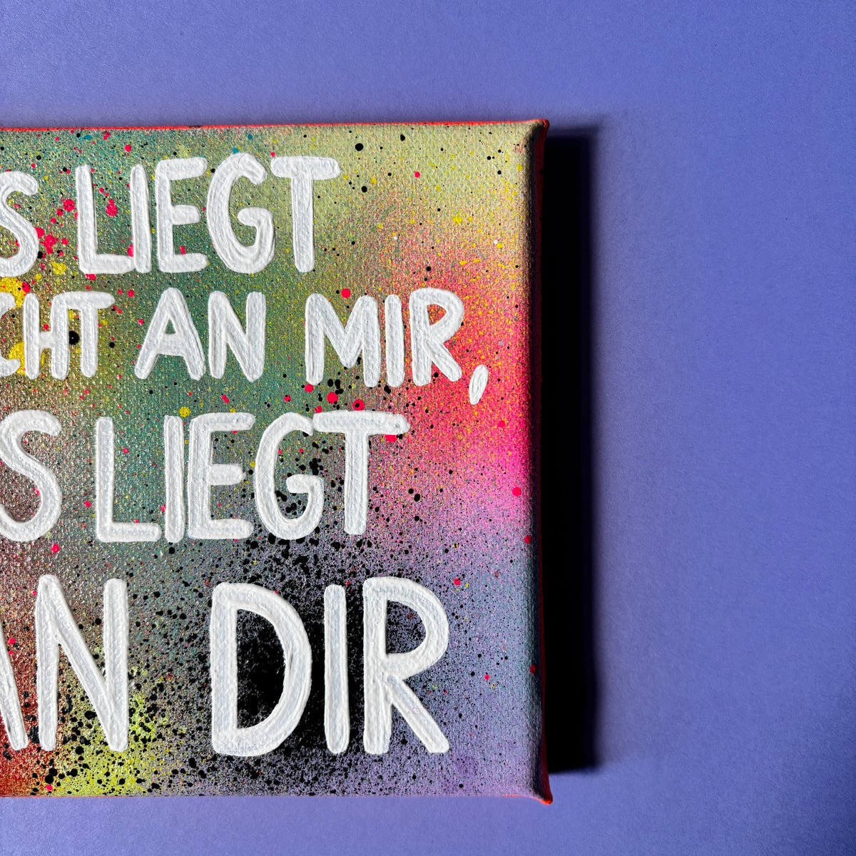 Bunt gesprühtes Kunstwerk mit weißem Schriftzug „Es liegt nicht an mir, es liegt an dir.“ von nahen