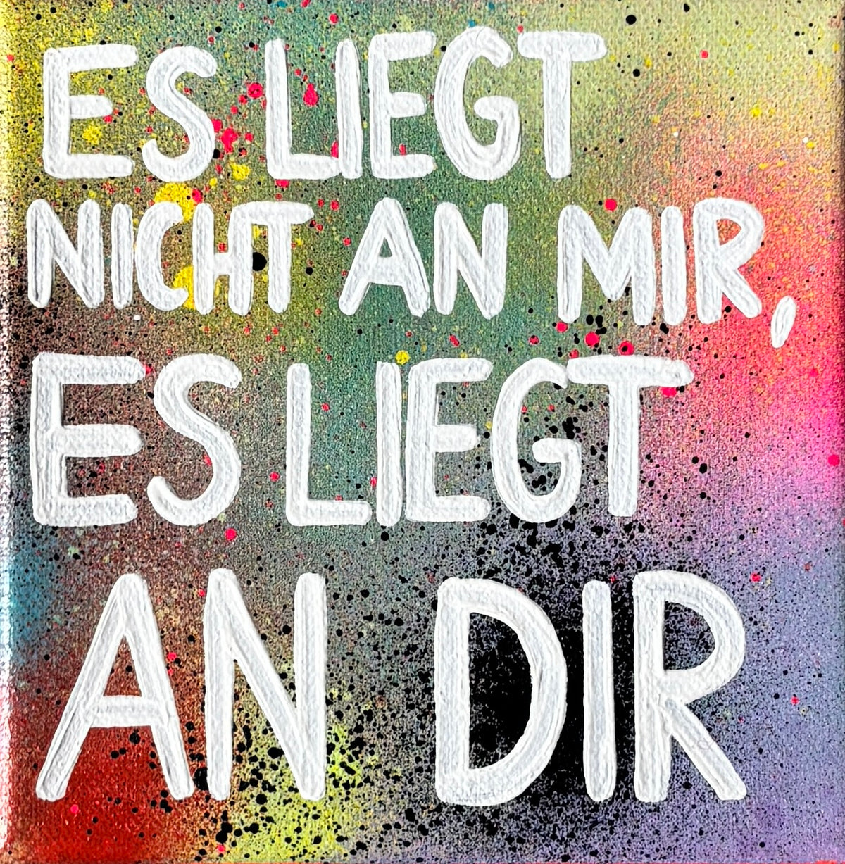 Bunt gesprühtes Kunstwerk mit weißem Schriftzug „Es liegt nicht an mir, es liegt an dir.“ im Ganzen