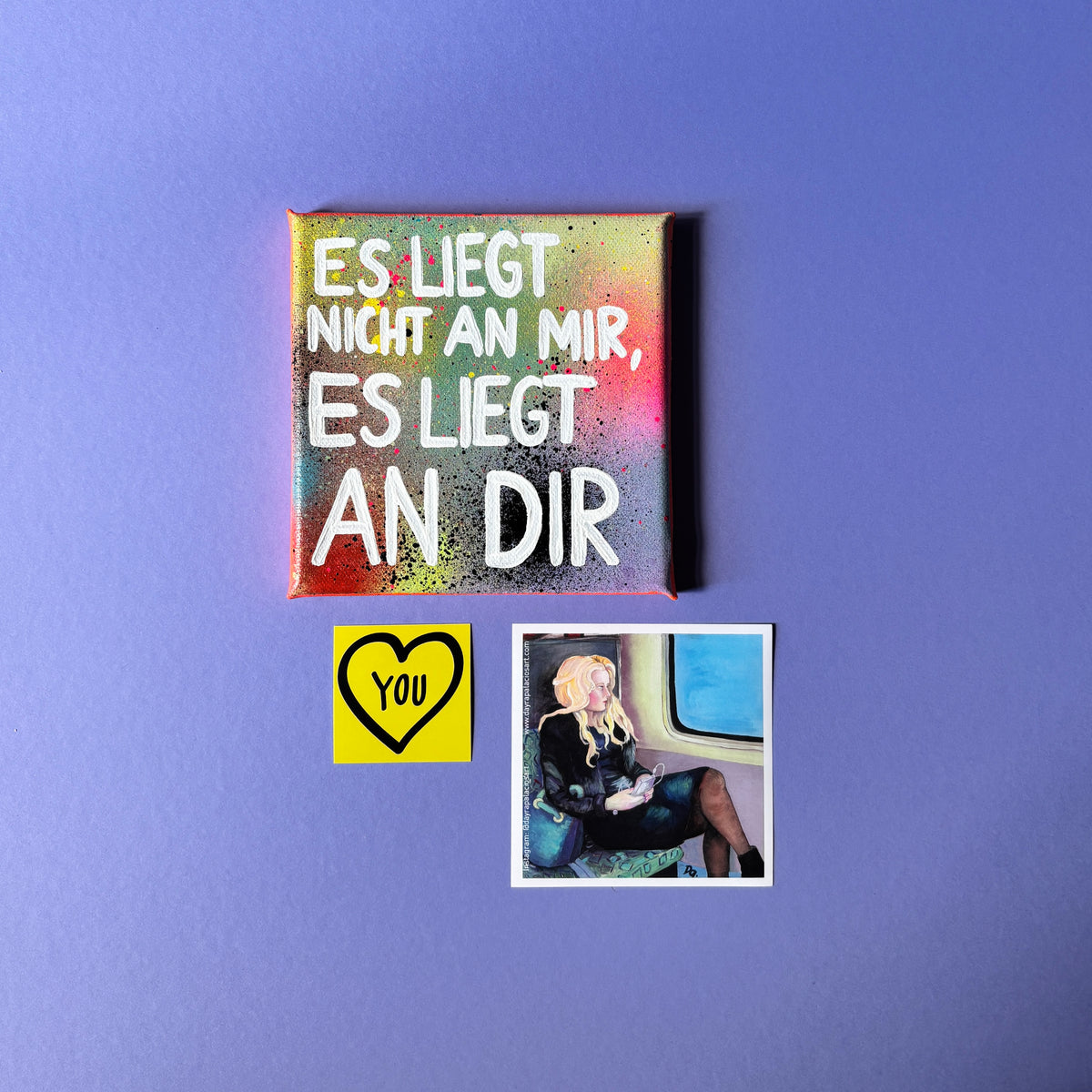 Bunt gesprühtes Kunstwerk mit weißem Schriftzug „Es liegt nicht an mir, es liegt an dir.“ Mit Sticker
