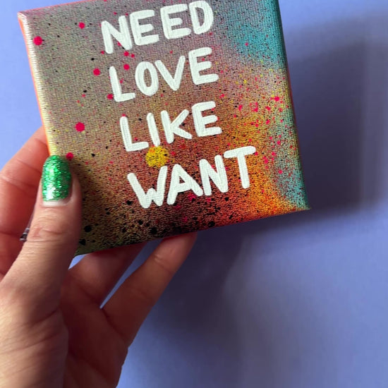 Bunt gesprühtes Kunstwerk mit weißem Schriftzug „Nieed Love Like Want“. Video. In der Hand haltend.